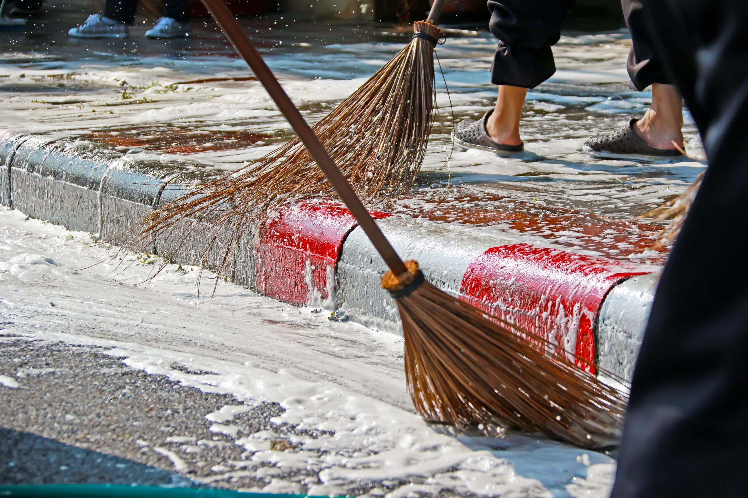 Close up broom worker cleaning dirty footpath